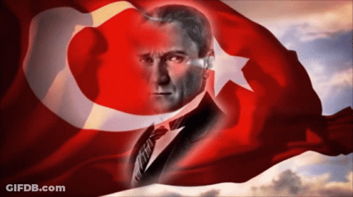 A Man In A Suit And Tie Is Behind A Turkey Flag GIF