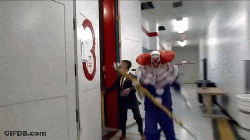 A Man In A Suit And Tie Is Being Attacked By A Clown In A Hallway . GIF