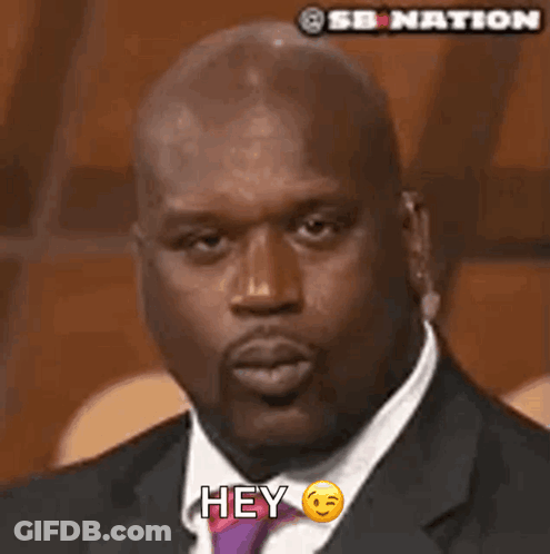A Man In A Suit And Tie Is Blowing A Kiss And Says Hey GIF