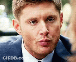 A Man In A Suit And Tie Is Blowing A Kiss At The Camera . GIF