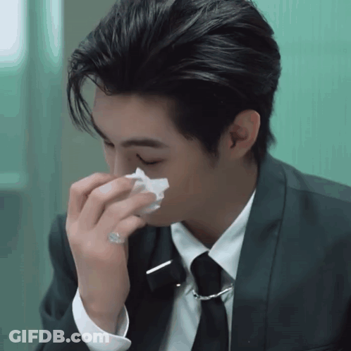 A Man In A Suit And Tie Is Blowing His Nose With A Napkin GIF