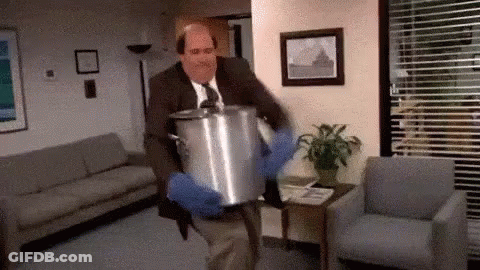 A Man In A Suit And Tie Is Carrying A Large Pot . GIF