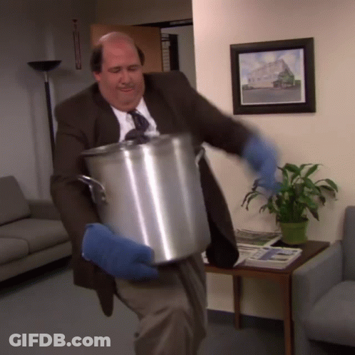 A Man In A Suit And Tie Is Carrying A Large Pot GIF