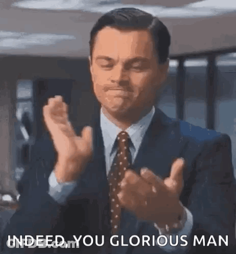 A Man In A Suit And Tie Is Clapping His Hands And Saying `` Indeed You Glorious Man '' . GIF
