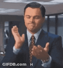 A Man In A Suit And Tie Is Clapping His Hands And Says H . GIF