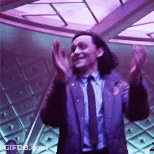 A Man In A Suit And Tie Is Clapping His Hands In A Room With Purple Lights . GIF