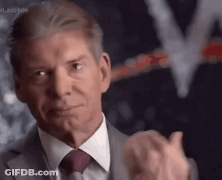 A Man In A Suit And Tie Is Clapping His Hands In Front Of A Blurred Background . GIF