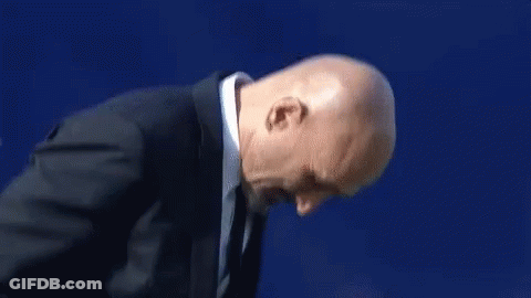 A Man In A Suit And Tie Is Clapping His Hands . GIF