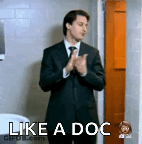A Man In A Suit And Tie Is Clapping His Hands With The Words Like A Doc Above Him GIF