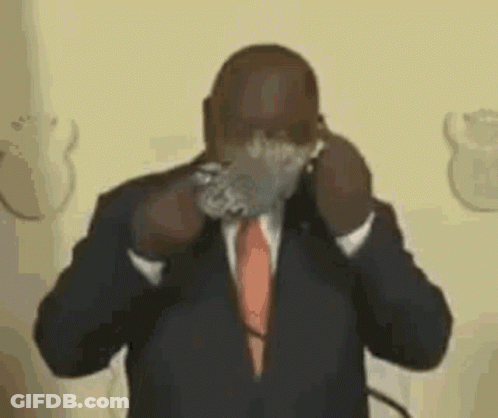 A Man In A Suit And Tie Is Covering His Face With A Piece Of Tape . GIF