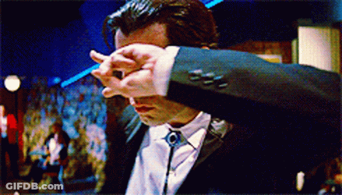 A Man In A Suit And Tie Is Covering His Face With His Hand GIF
