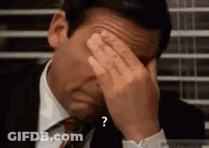 A Man In A Suit And Tie Is Covering His Face With His Hands With A Question Mark . GIF