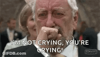 A Man In A Suit And Tie Is Crying While Covering His Mouth With His Hand . GIF