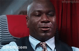A Man In A Suit And Tie Is Crying While Sitting On An Airplane . GIF