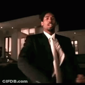 A Man In A Suit And Tie Is Dancing . GIF