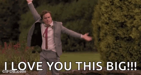 A Man In A Suit And Tie Is Dancing In A Park With His Arms Outstretched . GIF