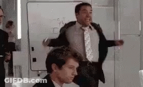 A Man In A Suit And Tie Is Dancing In A Room . GIF