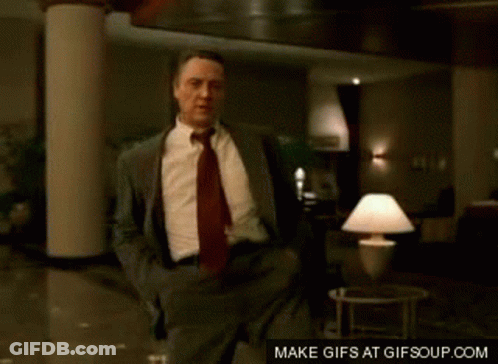 A Man In A Suit And Tie Is Dancing In A Room GIF