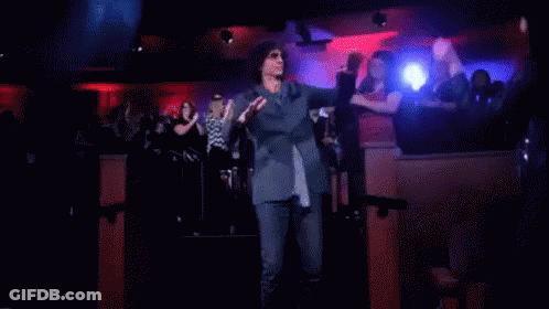 A Man In A Suit And Tie Is Dancing In Front Of A Crowd GIF