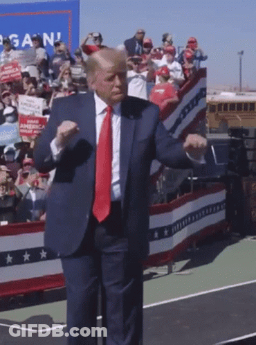 A Man In A Suit And Tie Is Dancing In Front Of A Crowd With A Sign That Says Again GIF