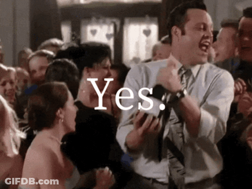 A Man In A Suit And Tie Is Dancing In Front Of A Crowd With The Word Yes Written On The Bottom GIF