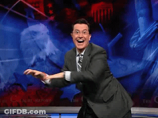 A Man In A Suit And Tie Is Dancing In Front Of A Screen That Says The C GIF