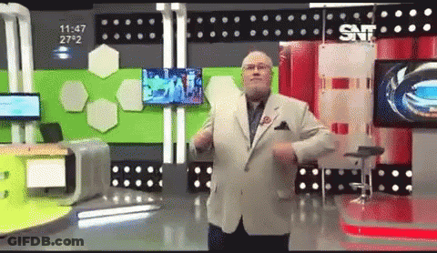 A Man In A Suit And Tie Is Dancing In Front Of A Snf Sign GIF