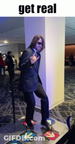 A Man In A Suit And Tie Is Dancing On A Dance Floor With The Words Get Real Below Him GIF