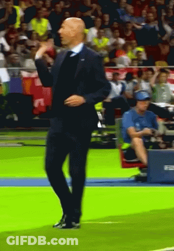 A Man In A Suit And Tie Is Dancing On A Field GIF