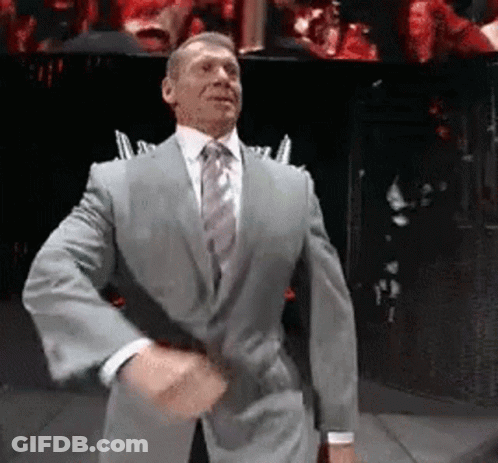 A Man In A Suit And Tie Is Dancing On A Stage In Front Of A Crowd . GIF