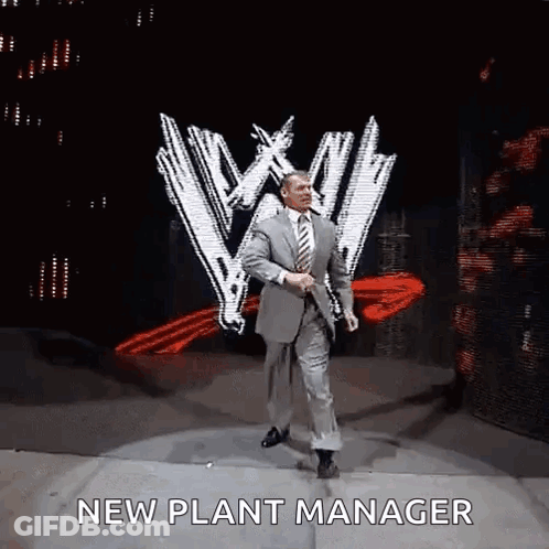 A Man In A Suit And Tie Is Dancing On A Stage With The Words `` New Plant Manager '' Written On It . GIF