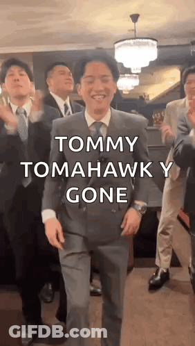 A Man In A Suit And Tie Is Dancing With A Group Of Men . GIF