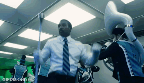 A Man In A Suit And Tie Is Dancing With A Man In A Blue Shirt That Says ' Miami ' On The Side GIF