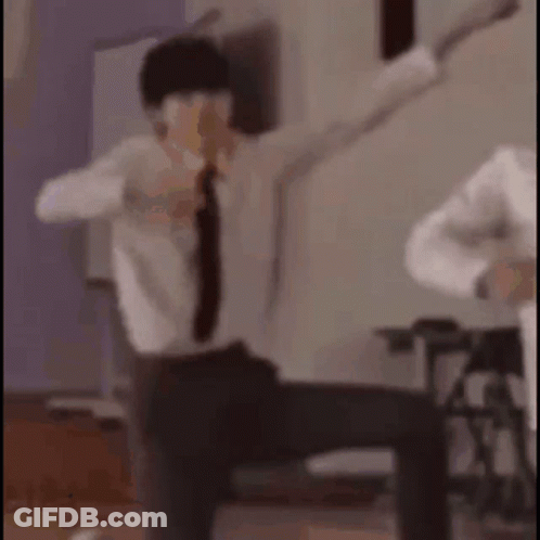 A Man In A Suit And Tie Is Dancing With His Arms Outstretched In A Room . GIF