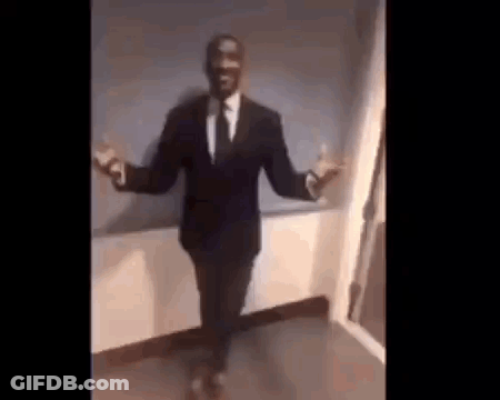 A Man In A Suit And Tie Is Dancing With His Arms Outstretched In A Room . GIF