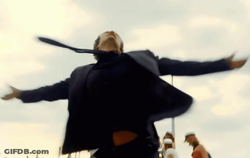 A Man In A Suit And Tie Is Dancing With His Arms Outstretched In The Air GIF