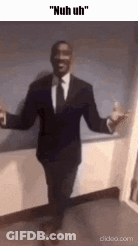 A Man In A Suit And Tie Is Dancing With His Arms Outstretched . GIF