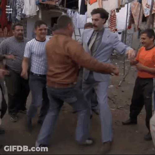 A Man In A Suit And Tie Is Dancing With Other Men GIF