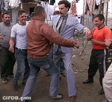 A Man In A Suit And Tie Is Dancing With Other Men GIF