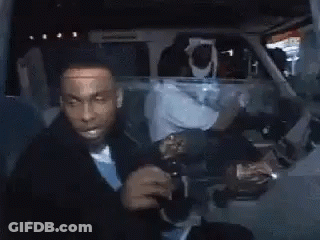 A Man In A Suit And Tie Is Drinking From A Bottle . GIF