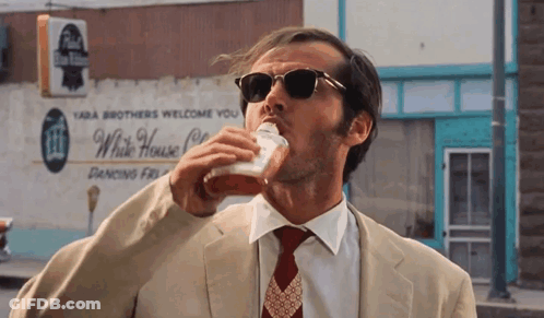A Man In A Suit And Tie Is Drinking From A Cup In Front Of A White House Restaurant GIF