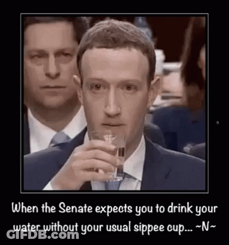 A Man In A Suit And Tie Is Drinking From A Glass . GIF