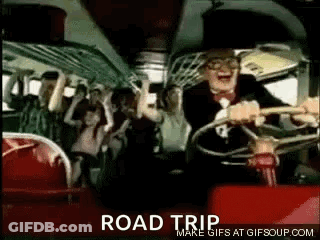 A Man In A Suit And Tie Is Driving A Bus With A Crowd Of People . GIF