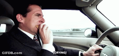A Man In A Suit And Tie Is Driving A Car While Crying . GIF