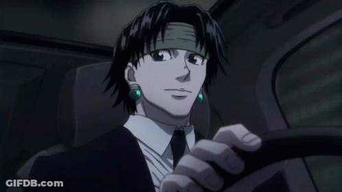 A Man In A Suit And Tie Is Driving A Car With Green Earrings GIF