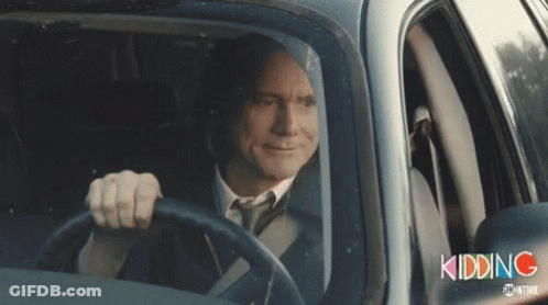 A Man In A Suit And Tie Is Driving A Car With The Word Kidding Written On The Side GIF