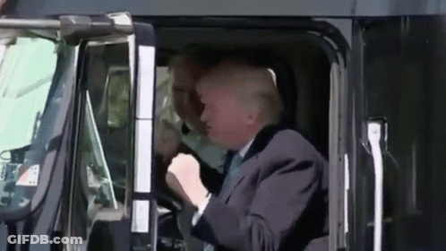 A Man In A Suit And Tie Is Driving A Truck GIF