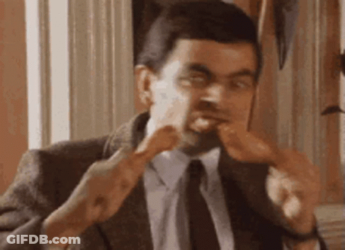 A Man In A Suit And Tie Is Eating A Chicken Wing . GIF