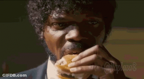 A Man In A Suit And Tie Is Eating A Hamburger With The Hashtag @Laplaza GIF