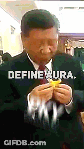 A Man In A Suit And Tie Is Eating A Hamburger With The Words Define Aura Written Below Him GIF